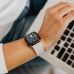 A person wearing a smartwatch working on a laptop, showcasing modern technology integration.